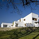 La maison se compose d’un rez-de-chaussée de 350 m² et d’un étage de 90 m². Côté sud, les escaliers qui mènent à la piscine. Les murs extérieurs sont en brique chaulés, recouverts de pierre de Chartres, de cuivre et de bois. Le toit est recouvert d’ardoises de Normandie.