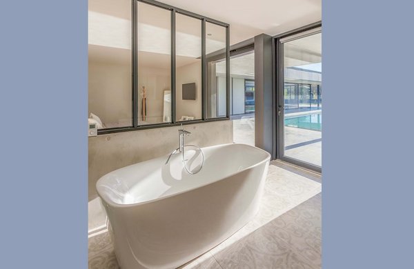 Seule la salle de bains bouscule la règle des contrastes avec du carrelage aux teintes similaires à celles du béton de la coursive.