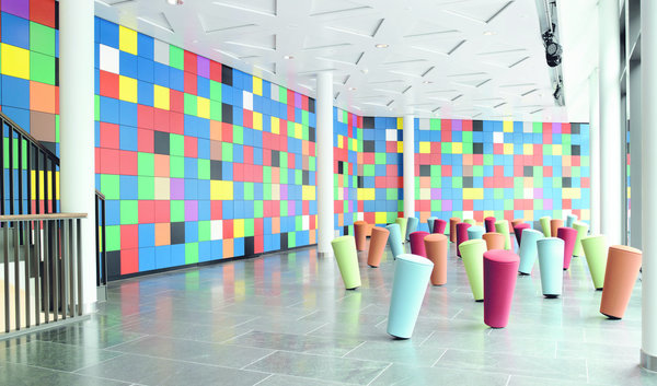 Polychromie ludique des tabourets Stand-Up édités par Wilkhahn pour cet espace d’accueil.