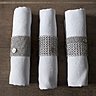Ronds de serviettes en maille fine, large, maille mixte, inox. En jouant avec les différentes grosseurs de maille, on peut créer des motifs géométriques, bandes et rayures, pour animer une serviette en lin blanc et la mettre en valeur. Création Foin® Cotte de mailles.