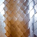 Le comptoir du bar a été recouvert de languettes d’aluminium brossé et découpé industriellement. Elles sont superposées comme des bandes horizontales pour figurer des écailles de poisson.