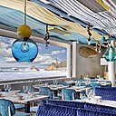 Des tissus d’ameublement (Pierre Frey, Nobilis, Dedar…) disposés comme des velums habillent le plafond et les sièges. Les ventilateurs et les appareils de chauffage au plafond sont passés aux couleurs du nouveau décor. Les luminaires font référence au domaine de la mer, de la voile et du bateau, ampoules sur cordages et abat-jours en verre soufflé qui jouent avec la lumière artificielle ou naturelle.