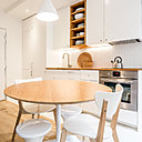 Dans la cuisine, on a installé une ligne de lumière, au-dessus du plan de travail, surmonté d’une crédence blanche à base de petits carreaux. Au sol, le carrelage suit le linéaire de la pièce. S'ajoute à cela la création d'un faux-plafond, avec spots lumineux encastrés dont la surface qui correspond à celle du carrelage du sol.