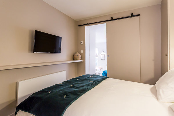 Une tablette a été créée sous l’écran TV et de chaque côté du lit, deux grands placards discrets assurent le rangement de la chambre.