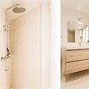 La salle de bains surfe sur les mêmes codes décoratifs que le reste de l'appartement : une lumière évanescente, un mobilier en bois clair et des revêtements (sol et murs) blancs qui subliment l'espace.