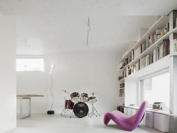 Un salon pour faire de la musique et qui intègre une bibliothèque et des rangements qui encadrent la fenêtre pour libérer de l’espace au sol.