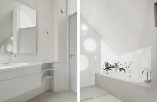 La salle de bains immaculée offre des rangements filants dans la continuité du plan vasque, qui épouse le volume de la pièce.