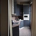 Avant : une cuisine avec un plan de travail et un sol en granit assorti très coloré et moucheté qui alourdit le petit volume de la cuisine. La teinte en contraste avec les placards manque d’élégance.