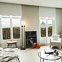 Dans le faux plafond sont cachés tous les réseaux et les boîtes des stores enrouleurs. Les grilles de la climatisation disparaissent dans les gorges pratiquées pour l’installation des stores. Fauteuils et guéridon, Silvera. Table basse, Cassina. Lampadaire, boules décoratives en résine orange et tabouret, Galerie Yvan Royer Posée au sol entre les deux fenêtres, une photo de Sébastien Patron.