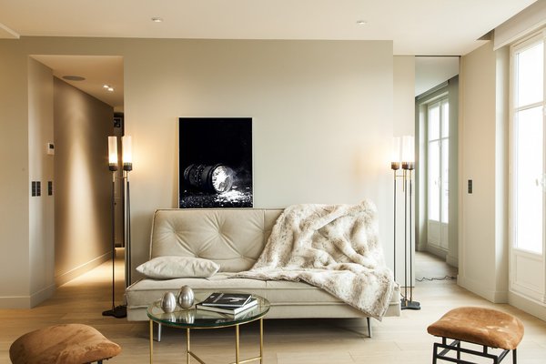Dans le séjour, de part et d’autre du canapé, on a pratiqué une double circulation et supprimé les portes encombrantes. A gauche, on accède à la cuisine. A droite, on rentre dans la chambre. Canapé Ligne Roset. Lampadaires et tabourets, Galerie Yves Royer. Table basse, Cassina. Au dessus du canapé, une photo de Sébastien Patron.