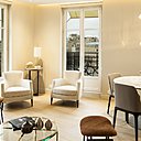Le séjour intègre un coin repas. Chaises, tables, fauteuils et guéridon, Silvera. Table basse, Cassina. Lampadaire, boules décoratives en résine orange et tabourets, Galerie Yvan Royer. Au sol, photo Sébastien Patron.