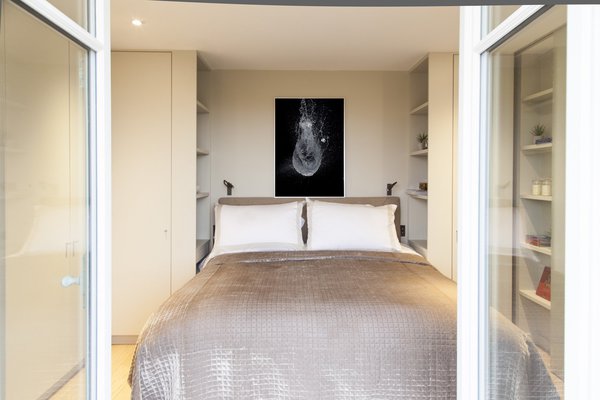 De part et d’autre du lit qui profite aussi de la belle vue sur Paris, des placards dressing et des niches chevets pour assurer le rangement de la pièce aux dimensions réduites lors de la rénovation.