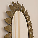 Gros plan sur un duo de miroirs ovales encadrés d’un décor de feuilles en métal doré vieilli et patiné.