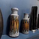 De part et d’autre de deux céramiques à la texture mouchetée, un vase et des photophores actuels en résine en contraste sur un mur bleu canard.