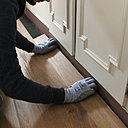 Etape 11 : découpe de la dernière rangée par report et assemblage pour terminer la pose. La dernière rangée assemblée, enlever les cales de revêtement de dilatation, couper l’excès de sous-couche le long des plinthes, et poser des plinthes coordonnées pour une finition parfaite.