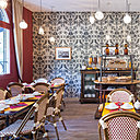 Papier à décor damassé (modèle Silvergate BP 817, Farrow and Ball) pour mettre en valeur un dressoir ancien dans la salle du petit déjeuner. Elle est meublée avec des sièges de terrasse en rotin de la maison Drucker, clin d’œil aux cafés du Midi et de Paris.