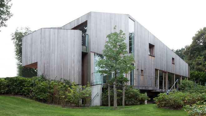 Les lames du bardage en bois à la teinte destinée à évoluer dans le temps s’accordent avec un garde-corps et des châssis en bois avec seuils de fenêtre en cuivre, qui offriront aussi une belle patine. Au second niveau, la terrasse enveloppante, avec garde-corps oblique qui vient terminer le volume extérieur, permet de protéger la chambre de l’une des filles des propriétaires du vis-à-vis de la maison voisine.