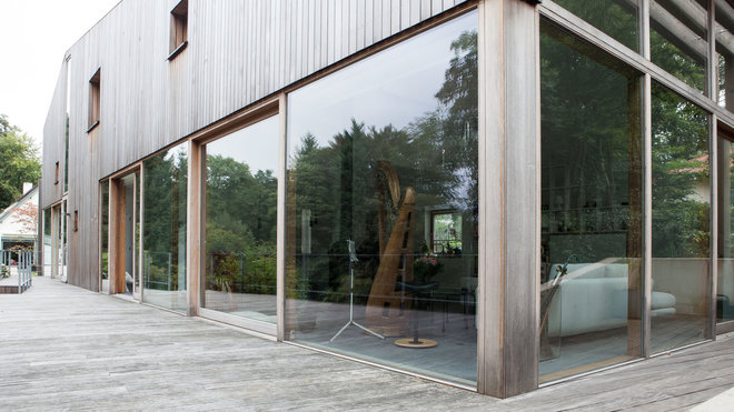 La terrasse en teck offre une patine grisée qui s’accorde ave celle du bardage de la maison.