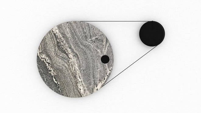 Horloge à courroie avec disque de gauche qui représente les minutes fait le tour en 1 heure et il entraîne grâce à la courroie les heures. L’axe du disque en granit possède un diamètre trois fois supérieur à celui du disque en métal. Grâce à un système de changement de vitesse, il tourne 12 fois plus vite (un tour par heure). Ces sont les minutes qui passent et entrainent le disque des heures.  Création Margaux Lafond et Ymer et Malta.