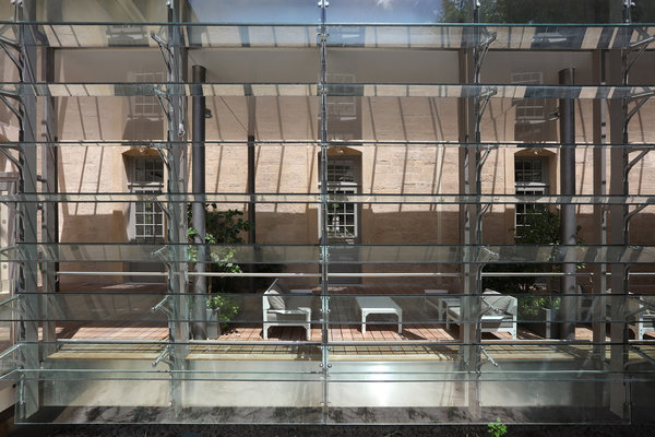 Extension et jardin d’hiver avec façade composée de lames en verre mobiles qui permettent de ventiler l’espace sans cacher le bâtiment restauré.