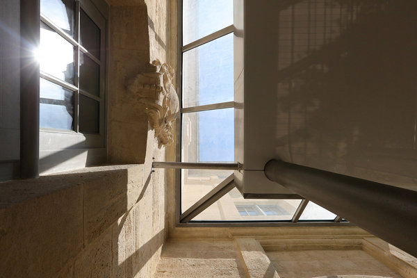 L’extension vitrée ne cache pas les détails architecturaux conservés et restaurés du bâtiment d’origine.