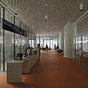 Au rez-de-chaussée, une façade entièrement transparente abrite un café, un restaurant, un magasin et un centre d'information. Ici, le plafond est recouvert de céramique, tandis que le sol est orange, se démarquant du pavé de béton bleu utilisé pour les espaces extérieurs.