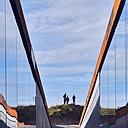 Les murs miroitants chapeautés d’acier patiné semblent sortir de la dune de terre et de sable.