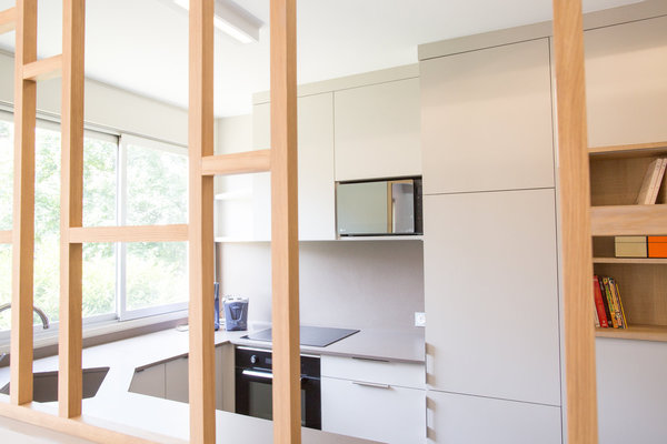 La cuisine est séparée du séjour par un claustra en chêne massif composé de sections de 35 x 35 mm. Son dessin quadrillé, léger et ajouré, dessiné sur mesure par Flora Auvray, fait écho au rangement global qui relie la cuisine à l’entrée.