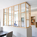 Au plafond, une bande de lumière serpente, intégrée dans un profilé en staff découpé. Comme le meuble, elle relie l’entrée à la cuisine et sa géométrie répond au claustra en chêne. Ce matériau chaleureux et aussi décliné dans les niches du rangement et réveille la neutralité du reste de l’espace.