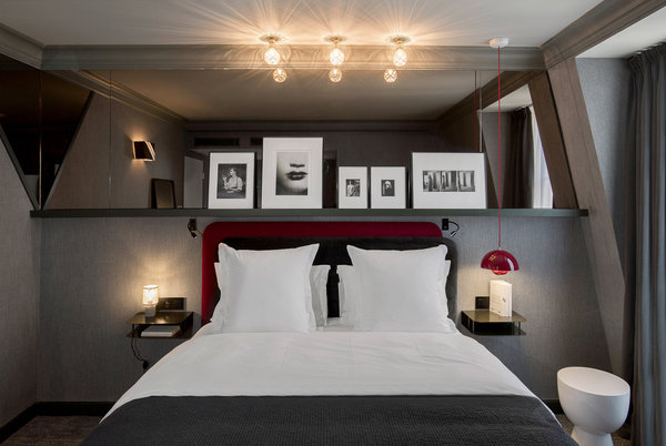 Harmonie de gris ponctuée de rouge pour cette chambre qui s’inspire des tissus des tailleurs masculins. Papier-peint Arte, collection Flamand.