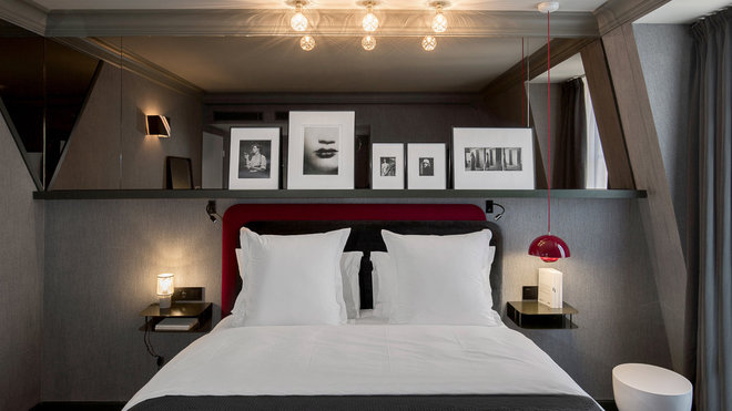 Harmonie de gris ponctuée de rouge pour cette chambre qui s’inspire des tissus des tailleurs masculins. Papier-peint Arte, collection Flamand.