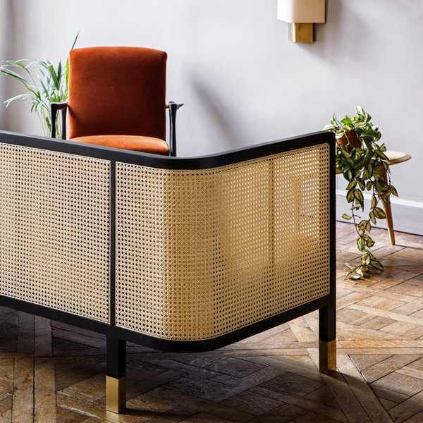 Le dossier du canapé met en exergue le beau travail du cannage, dans une version moderne et raffinée.