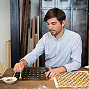 Après impression de la première couleur du motif, chaque feuille est colorée à la main à l’aide d’un pochoir. Ici, Vincent réalise la teinte jaune du décor n° 5.