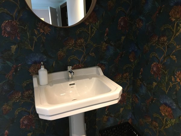 Modèle Wild Artichokes : des artichauts en fleurs version colorama aux teintes délavées sur fond avec effet de tissage se mêlent à des vols d’oiseaux exotiques pour personnaliser un coin lavabo. Version in Blue ou in Black. l 100 cm.