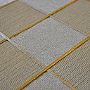 Gros plan sur un travail de damiers en cordes de lin bicolores rehaussés et sertis de galons, couleur ivoire et or. Collection Marqueté.