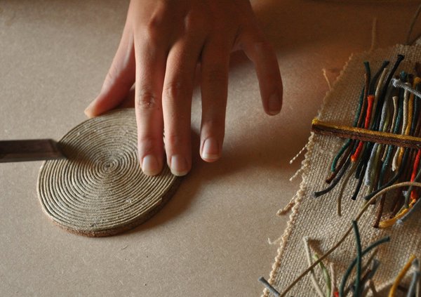 Véronique de Soultrait travaille des modules circulaires en corde souple (3 mm de diamètre) qu’elle plaque sur des panneaux muraux gainés pour créer des compositions graphiques.