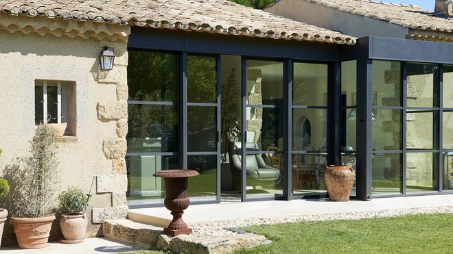 La finesse des profilés et leur couleur « noir sablé » contribuent à l’effacement des ouvertures. Cette esthétique minimaliste, associée aux traverses horizontales, confère un style contemporain à la bâtisse provençale.