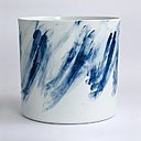 A gauche, vase en porcelaine émaillée avec traces de couleur essuyées sur ses parois extérieures. Vase, Piet Stockmans, 2012. A droite, dans une boîte en bois empilement pyramidal d’assiettes circulaires qui évoque la rétractation de la porcelaine pendant la cuisson, avec coulure de bleu latéral. Round dishes, Piet Stockmans, 2017.