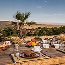 En extérieur, la table est dressée en toute simplicité, face à la vue époustouflante sur le désert.