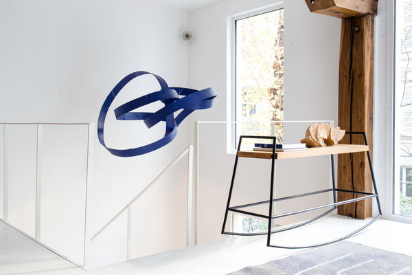 L’escalier tout blanc se fond dans l’espace pour laisser place au mobile de Jacques Salles et à une console.