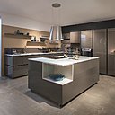 Elle a tout d’une cuisine de pro avec ses placards sans poignées. Modèle Gaia, façades laquées sépia brillant, plan de travail quartz olympe Calcatta.