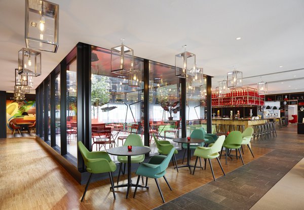 Au milieu du lobby de citizenM gare de Lyon, est implanté le patio vitré. D’un côté le bar et la cuisine ouverte et de l’autre societyM, zone composée de salles de réunion.