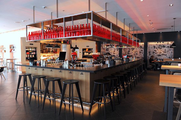 Au centre du lobby du citizenM la Défense, un bar en ilot permet aux hôtes de se retrouver ; il fait partie du programme d’aménagement intérieur mené par l’agence d’architecture intérieure Concrete.
