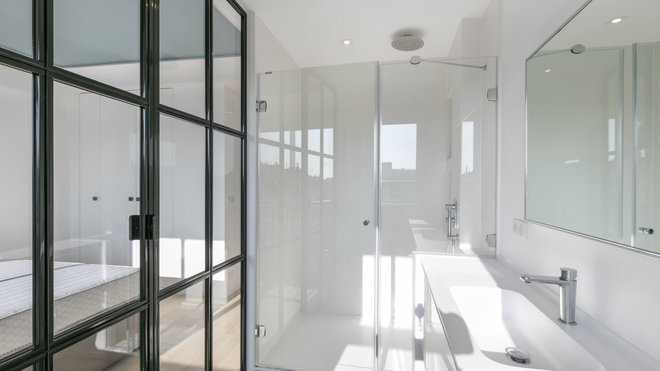 Dans la salle de bains, un grand bac à douche de 130 x 90 cm derrière des portes en verre qui laissent passer la lumière. Un plan avec vasque sculptée dans la masse en Corian ®. Robinetterie, Dornbracht.