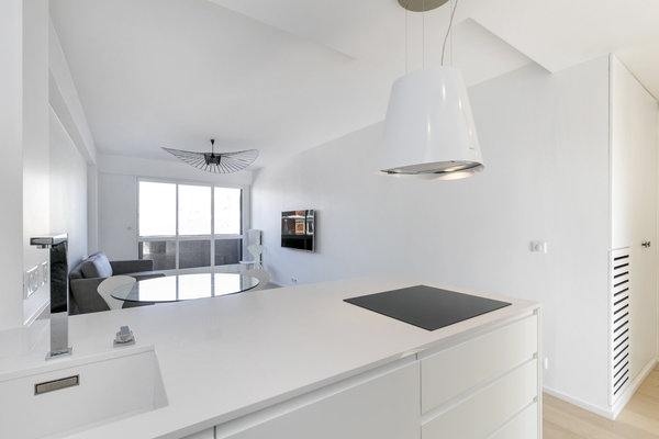 Les meubles de la cuisine font office de séparation de pièce. Plan de travail et vasque en Silestone. Robinetterie, Dornbracht. Dans le salon, suspension Vertigo, modèle taille moyenne, création Constante Guisset pour Petite Friture.