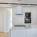 Pour éclairer la partie cuisine, des spots ont été intégrés dans une gorge pratiquée en creux dans le faux plafond. La ligne noire des spots en saillie s’accompagne d’un éclairage à base de Leds invisibles.