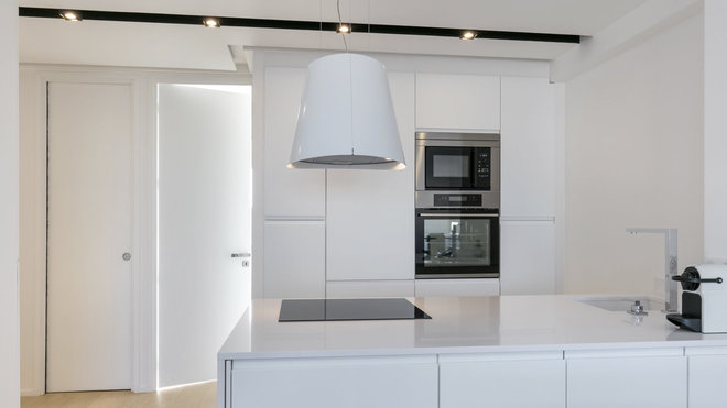 Pour éclairer la partie cuisine, des spots ont été intégrés dans une gorge pratiquée en creux dans le faux plafond. La ligne noire des spots en saillie s’accompagne d’un éclairage à base de Leds invisibles.