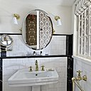 Dans les salles de bains aux lignes Art déco, du marbre et du laiton, pour évoquer les débuts de la modernité. Un papier-peint d’esprit Art and Craft se reflète dans le miroir.