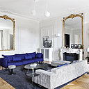 Dans le salon, murs peints avec le coloris Strong White, peintures Farrow and Ball. Canapé, modèle Gentry bleu roi de Moroso. Canapé, chez Poltrona Frau, avec repose-pieds recouvert de tissu par Petites Mains à la carte. Sellettes en métal laqué noir, chez AM.PM. Appliques en céramique AM.PM. Suspensions Aim, création Ronan et Erwan Bouroullec chez Flos. Tapis en pure laine, réalisé sur mesure, chez Annie Pate. Tables basses de forme libre, AM.PM.