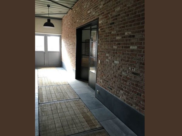 Murs en briques anciennes intégrant des éléments peints de teinte claire. Sol avec banches en bois (éléments de coffrages), provenant de murs anciens, et associés à des dalles en pierre bleue neuve.